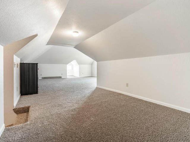 additional living space with vaulted ceiling, a baseboard radiator, carpet flooring, and baseboards