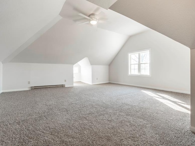 additional living space with carpet flooring, a ceiling fan, baseboards, vaulted ceiling, and baseboard heating