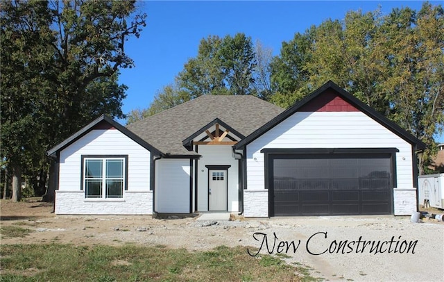 view of front facade with a garage, stone siding, and roof with shingles