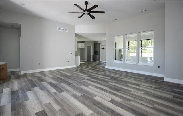 unfurnished living room featuring a ceiling fan, visible vents, and baseboards