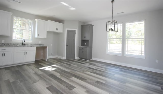 kitchen featuring hanging light fixtures, light wood-type flooring, a sink, and baseboards