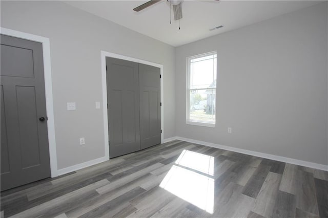 unfurnished bedroom featuring visible vents, ceiling fan, baseboards, and wood finished floors