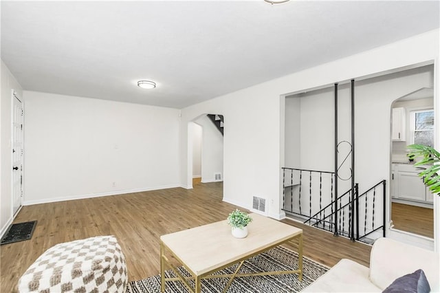 living area with visible vents, arched walkways, and wood finished floors