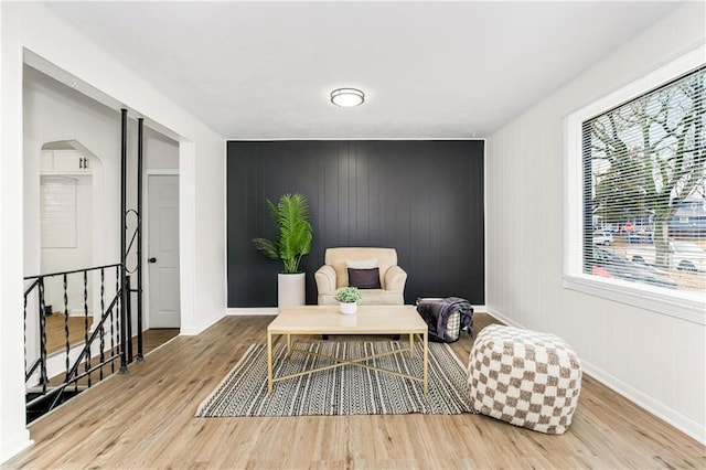 living area featuring arched walkways, plenty of natural light, and wood finished floors