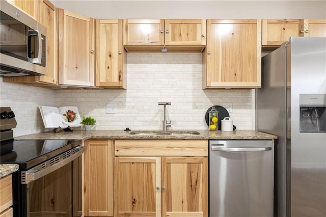 kitchen with appliances with stainless steel finishes, light brown cabinets, a sink, and decorative backsplash