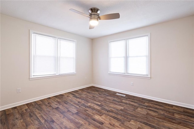 unfurnished room featuring ceiling fan, visible vents, baseboards, and dark wood-style flooring