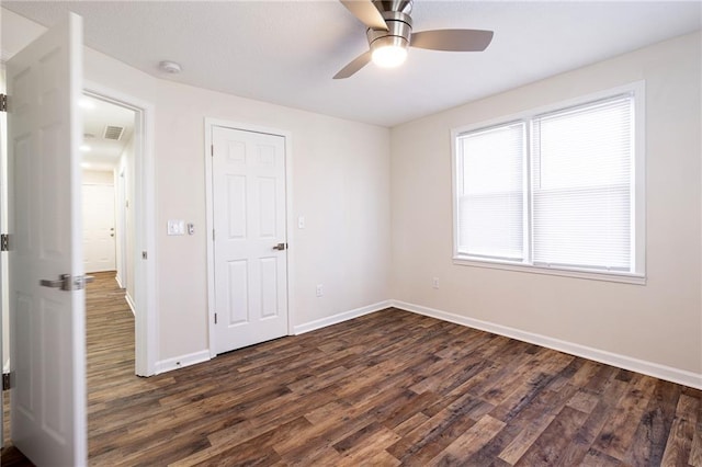 spare room featuring dark wood-type flooring, visible vents, ceiling fan, and baseboards