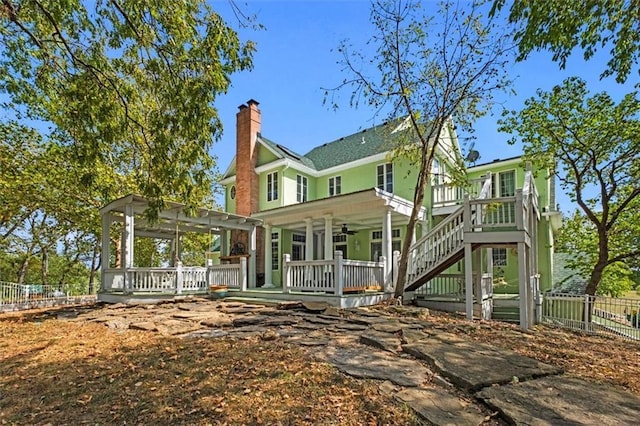 back of property featuring ceiling fan, a chimney, stairway, covered porch, and fence