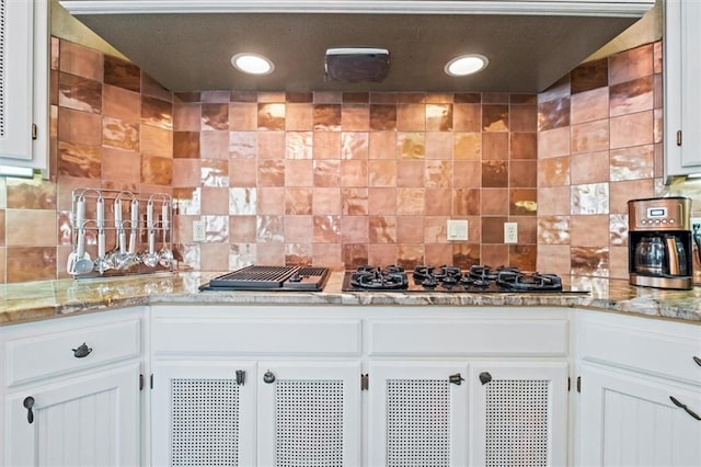 kitchen featuring light stone counters, recessed lighting, decorative backsplash, white cabinetry, and black gas stovetop