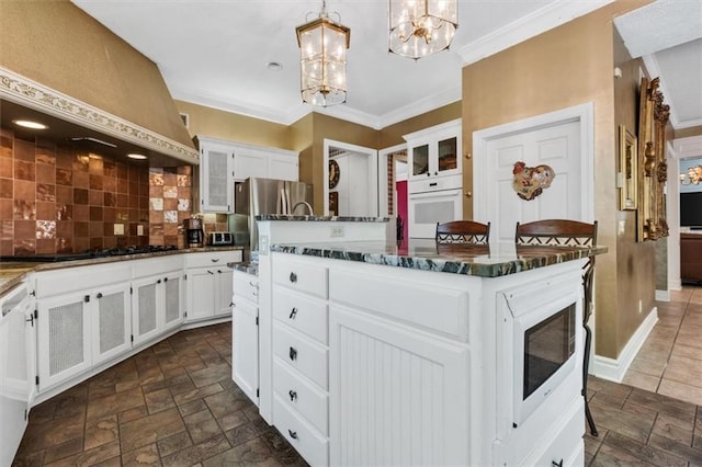 kitchen with stone tile flooring, oven, premium range hood, and freestanding refrigerator