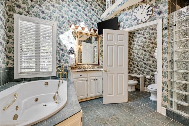 full bathroom with wallpapered walls, toilet, a whirlpool tub, vanity, and a bidet