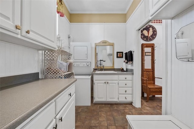 kitchen featuring a sink, white cabinets, light countertops, ornamental molding, and stacked washer and clothes dryer