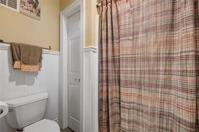 bathroom featuring toilet and wainscoting