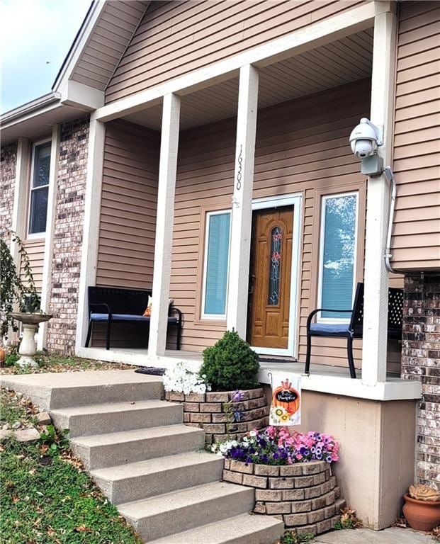 doorway to property with covered porch and brick siding