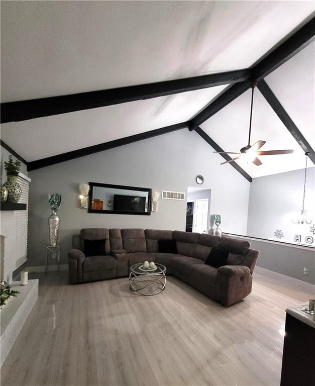 living area featuring baseboards, visible vents, wood finished floors, vaulted ceiling with beams, and a fireplace