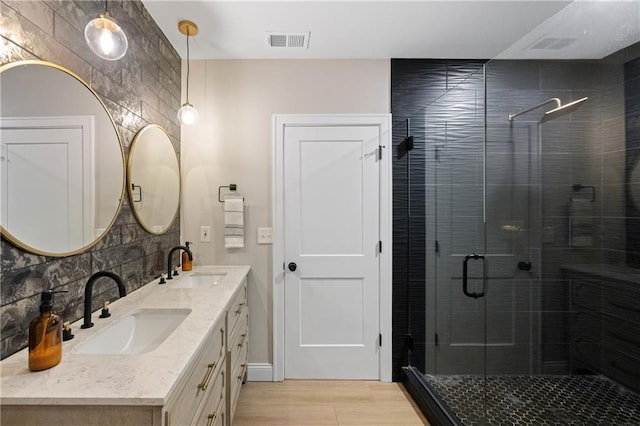 full bath with a sink, visible vents, double vanity, and a shower stall