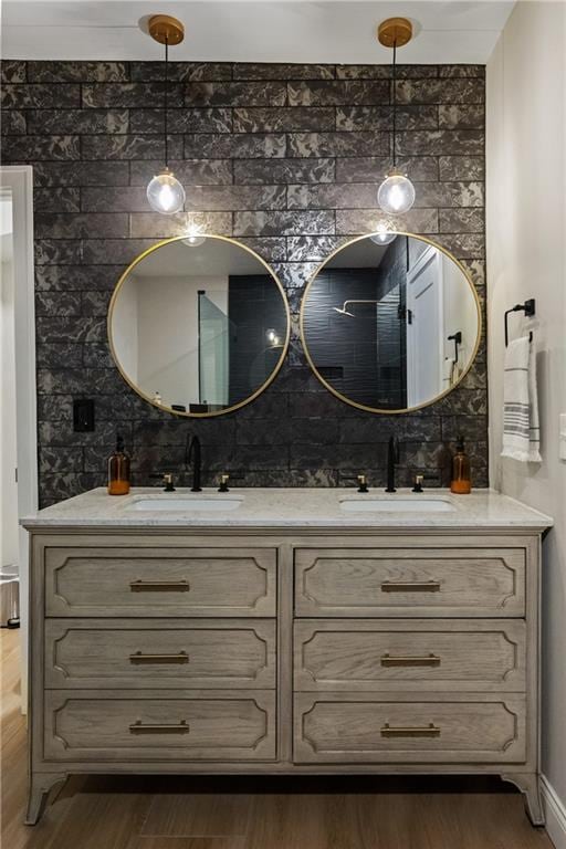 bathroom with double vanity, wood finished floors, backsplash, and a sink