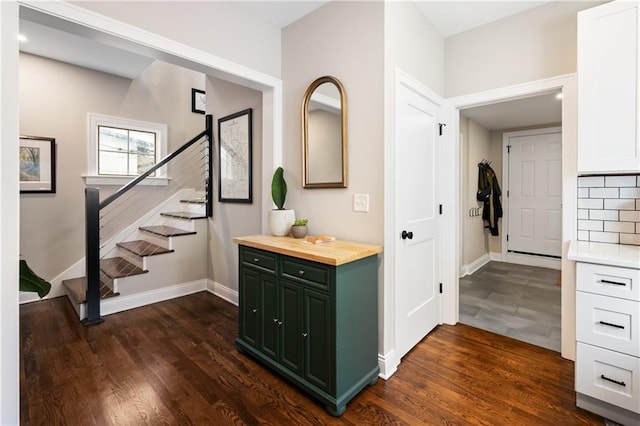 hallway with dark wood finished floors, stairway, and baseboards