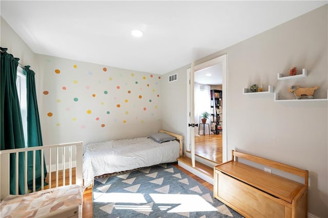 bedroom with visible vents, baseboards, and wood finished floors