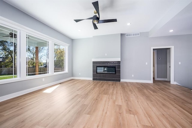 unfurnished living room with a ceiling fan, a glass covered fireplace, visible vents, and baseboards