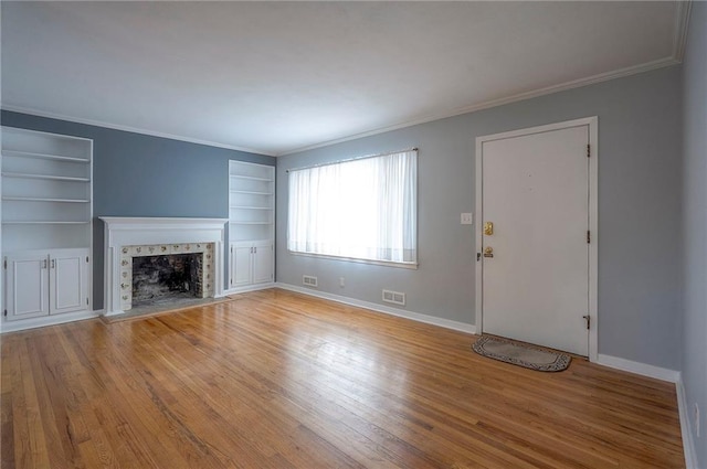 unfurnished living room with crown molding, a fireplace, visible vents, light wood-style flooring, and baseboards