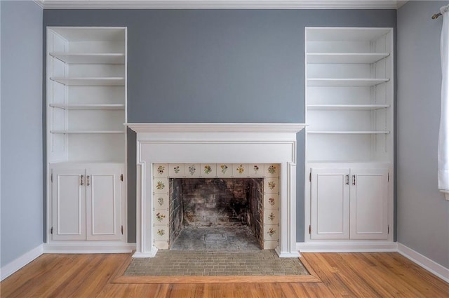 unfurnished living room featuring baseboards, a tiled fireplace, and wood finished floors