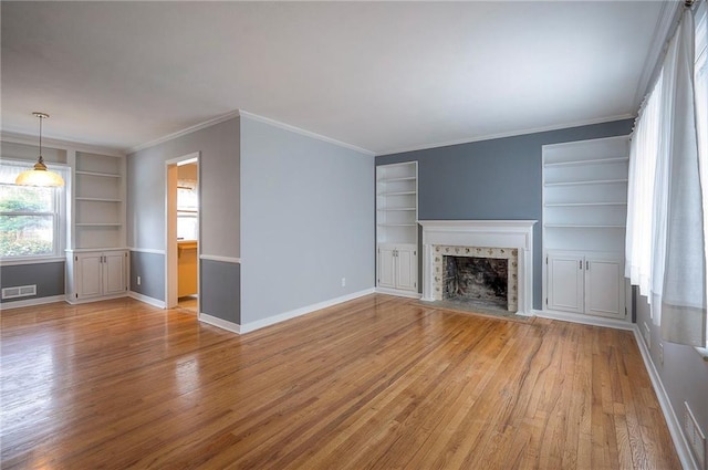 unfurnished living room featuring visible vents, a tiled fireplace, baseboards, and wood finished floors