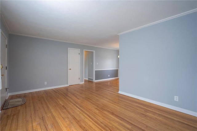 spare room with baseboards, crown molding, visible vents, and light wood finished floors