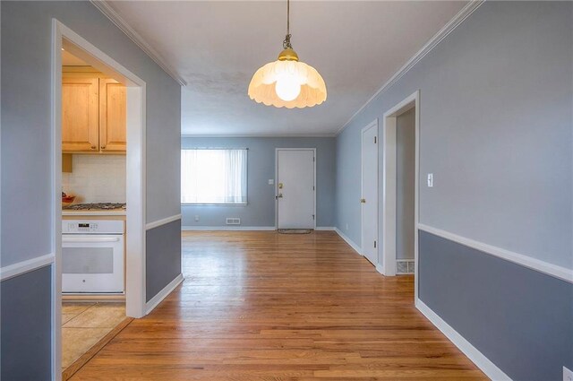 interior space featuring baseboards, ornamental molding, and light wood-style floors