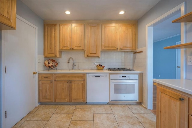 kitchen featuring white appliances, decorative backsplash, light countertops, and a sink