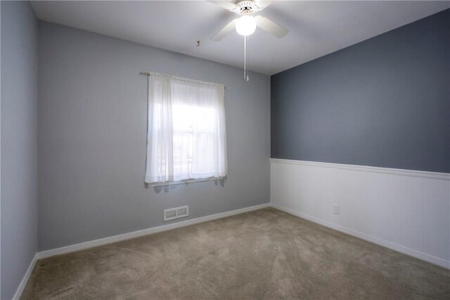 carpeted empty room featuring ceiling fan, visible vents, and baseboards