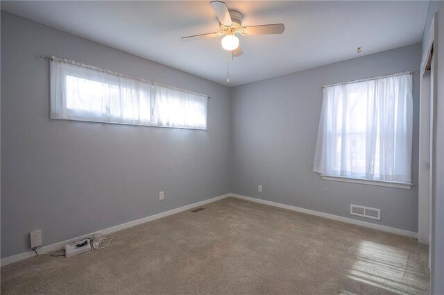 spare room featuring ceiling fan, carpet flooring, visible vents, and baseboards