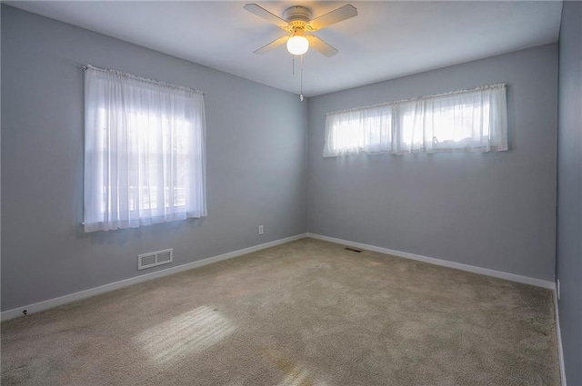 unfurnished room featuring carpet floors, baseboards, visible vents, and ceiling fan