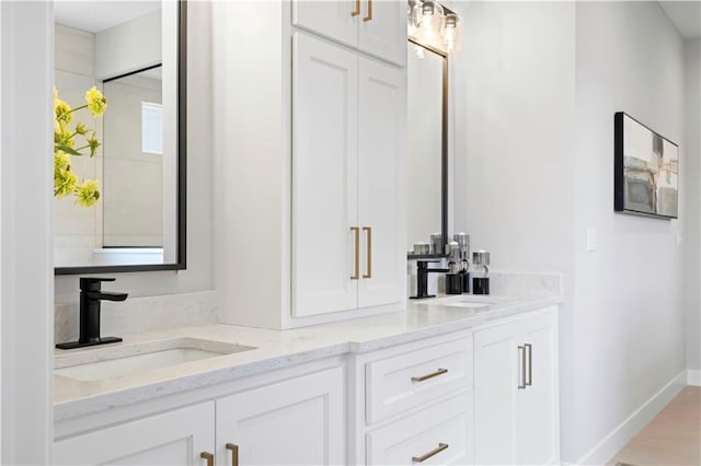 full bathroom featuring double vanity and baseboards