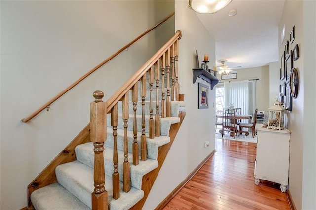 staircase featuring wood-type flooring, ceiling fan, and baseboards