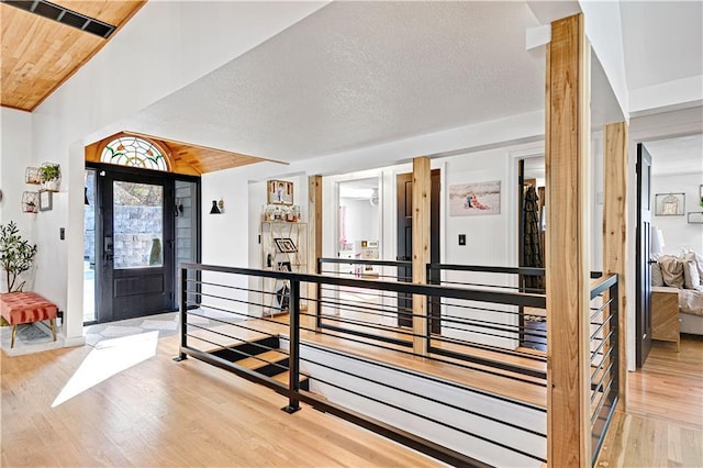 entryway with visible vents, lofted ceiling, wood ceiling, a textured ceiling, and light wood-type flooring