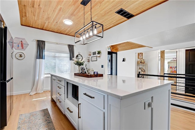 kitchen with wood ceiling, white cabinets, light countertops, light wood-type flooring, and freestanding refrigerator