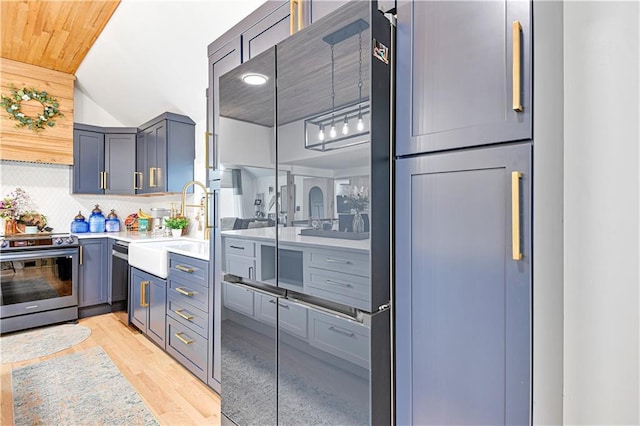 kitchen featuring tasteful backsplash, stainless steel electric range oven, light countertops, light wood-type flooring, and a sink