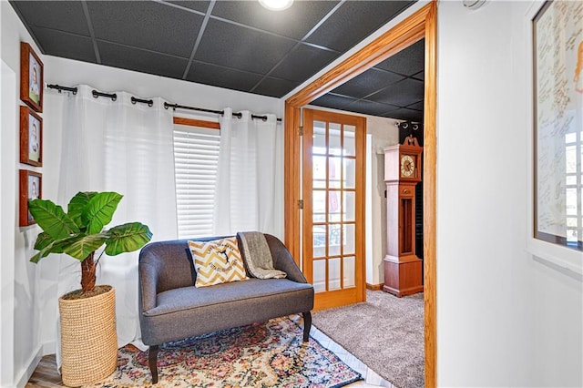 sitting room featuring carpet flooring, a paneled ceiling, and baseboards