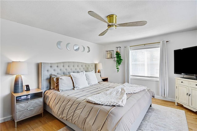 bedroom with light wood-style floors, a textured ceiling, baseboards, and a ceiling fan