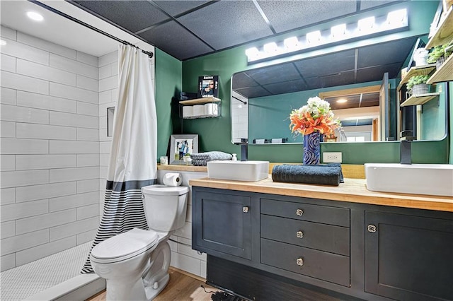 full bathroom with wood finished floors, tiled shower, vanity, and toilet