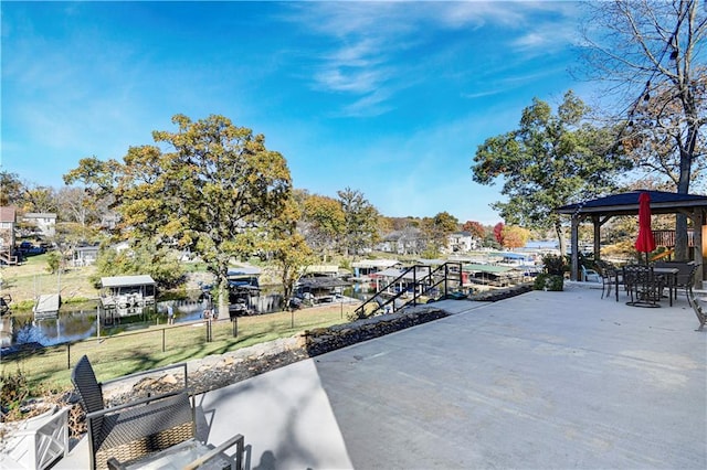 view of patio featuring a water view, fence, and a gazebo