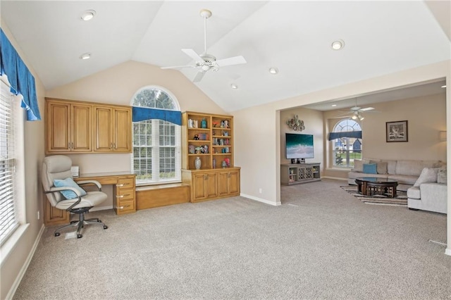home office with vaulted ceiling, baseboards, light colored carpet, built in study area, and ceiling fan
