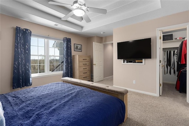 bedroom featuring baseboards, visible vents, carpet, a ceiling fan, and a walk in closet