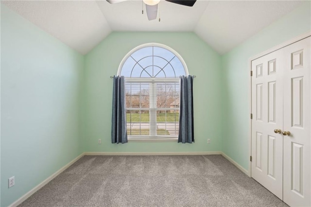 unfurnished bedroom featuring carpet, lofted ceiling, baseboards, and ceiling fan