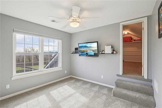 interior space featuring baseboards, a ceiling fan, visible vents, and carpet floors