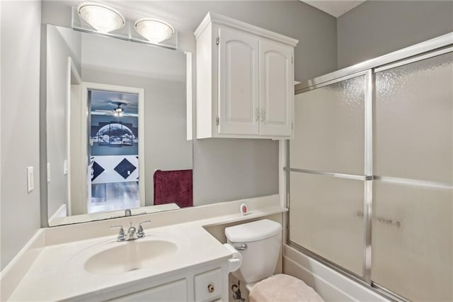 full bathroom featuring combined bath / shower with glass door, toilet, and vanity