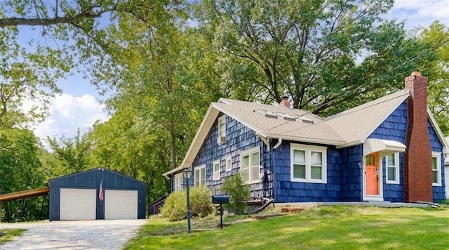 view of front facade with a chimney, a front lawn, a detached garage, and an outdoor structure