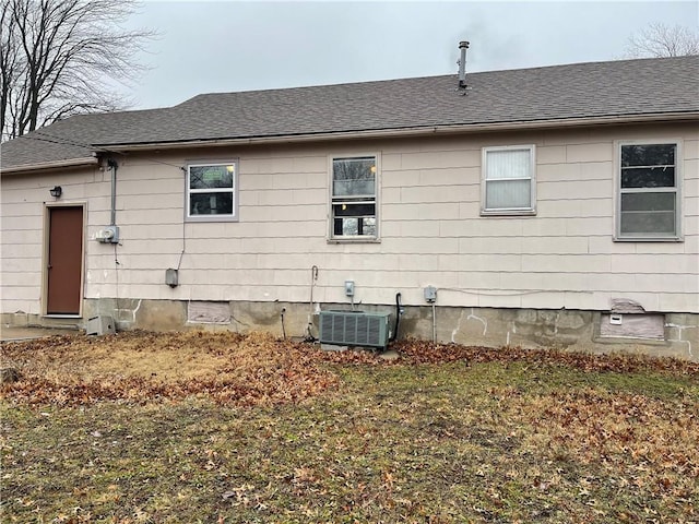 rear view of house featuring crawl space, cooling unit, and roof with shingles