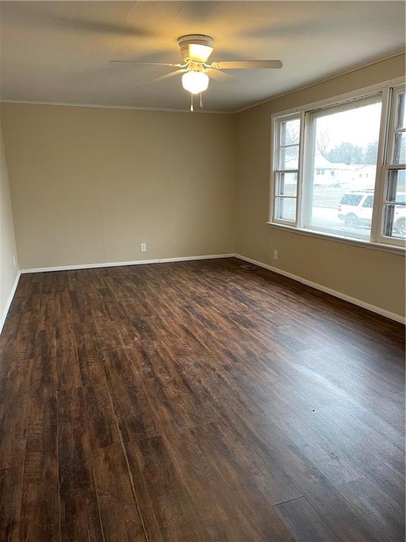 empty room with ceiling fan, dark wood-type flooring, and baseboards